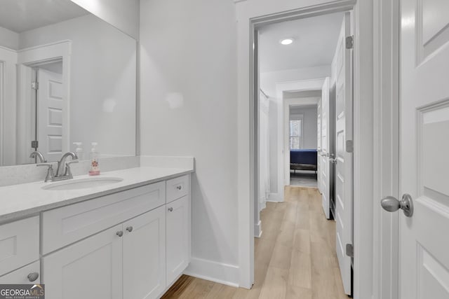 bathroom featuring baseboards, wood finished floors, and vanity