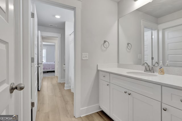 bathroom with ensuite bathroom, wood finished floors, vanity, and baseboards