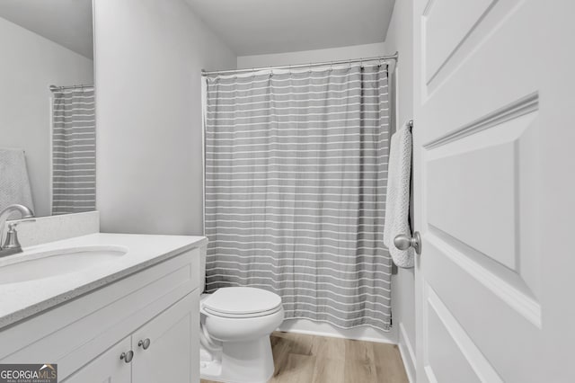 bathroom with toilet, wood finished floors, and vanity