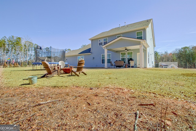 rear view of house featuring a trampoline, a yard, and ceiling fan