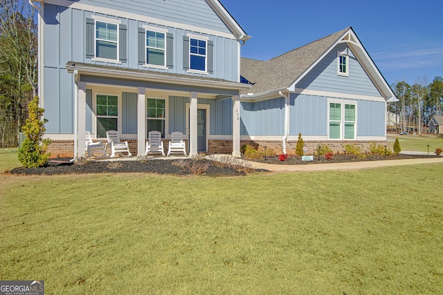 view of front of property featuring a front lawn, a porch, and brick siding