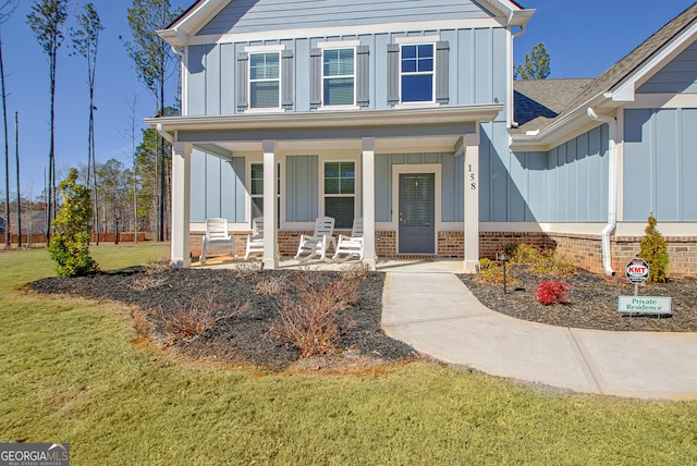 view of front facade featuring board and batten siding, a front yard, roof with shingles, and a porch