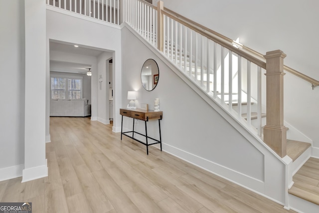 stairway with a high ceiling, baseboards, and wood finished floors