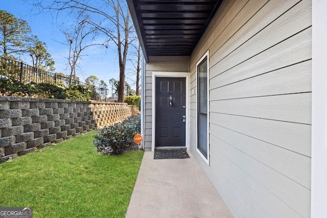 property entrance featuring fence and a yard