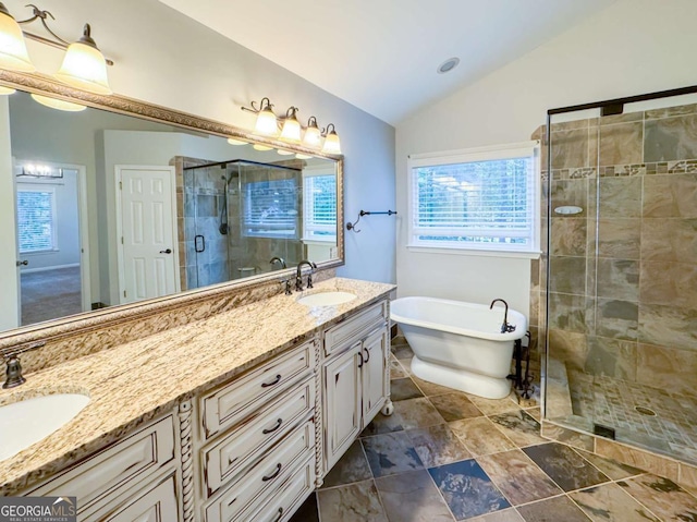 full bathroom featuring a stall shower, a freestanding bath, vaulted ceiling, and a sink