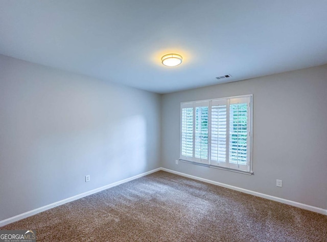 empty room with carpet, visible vents, and baseboards