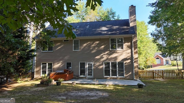 rear view of property with a fenced backyard, a lawn, a chimney, a patio area, and a hot tub