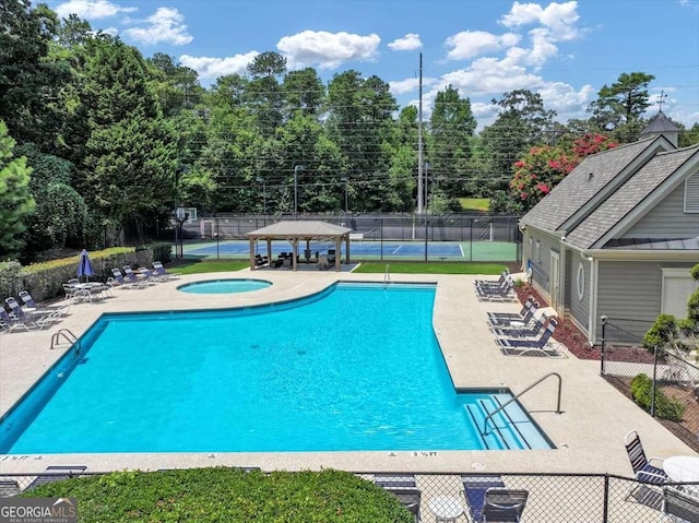 pool with a patio area, a hot tub, fence, and a gazebo