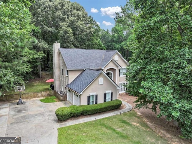 view of front facade featuring a chimney, stucco siding, a shingled roof, concrete driveway, and fence