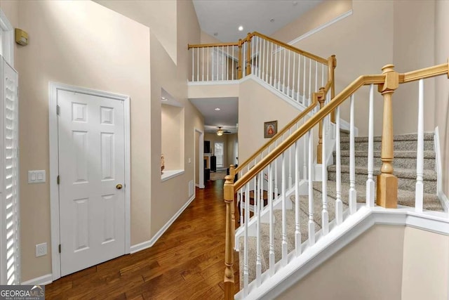 entrance foyer with stairs, dark wood-type flooring, a high ceiling, and baseboards