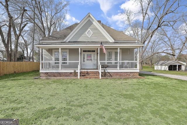 view of front of home featuring covered porch, a shingled roof, fence, a chimney, and a front yard