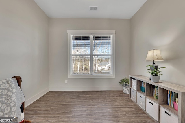 living area with baseboards, visible vents, and wood finished floors