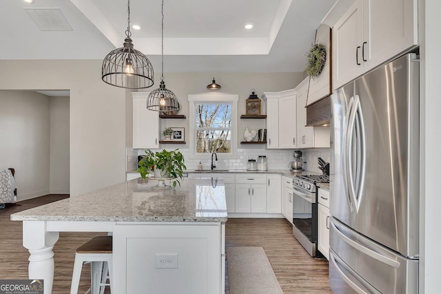 kitchen with visible vents, a tray ceiling, stainless steel appliances, open shelves, and a sink