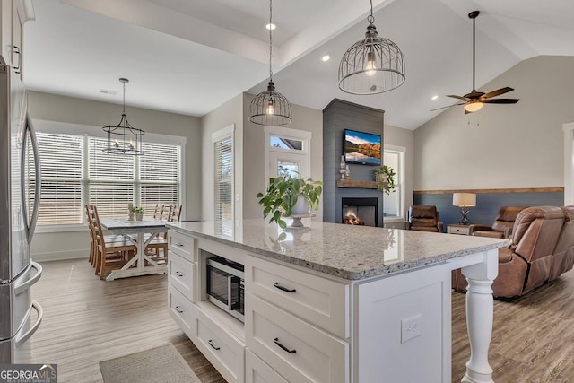 kitchen with appliances with stainless steel finishes, a large fireplace, a healthy amount of sunlight, and wood finished floors