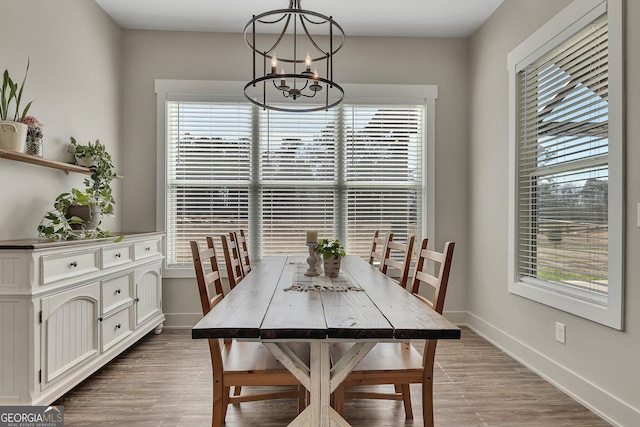 dining room with light wood-style flooring, baseboards, and a notable chandelier