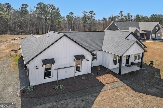 view of front facade featuring a shingled roof, a patio, metal roof, a standing seam roof, and board and batten siding