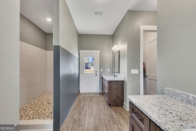 bathroom featuring visible vents, tiled shower, wood finished floors, and vanity