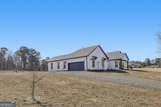 view of front of house featuring dirt driveway, a front lawn, and an attached garage