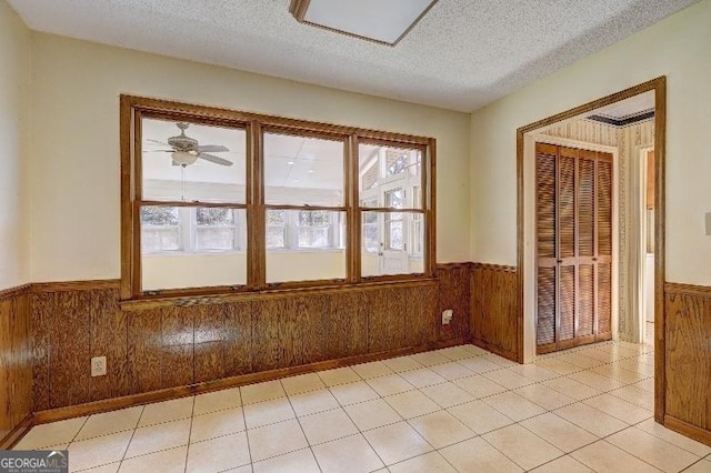 unfurnished room with a wainscoted wall, wood walls, and a textured ceiling