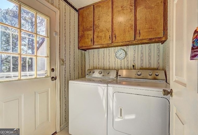 clothes washing area featuring cabinet space, washer and clothes dryer, and wallpapered walls