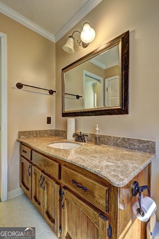 bathroom featuring tile patterned flooring, ornamental molding, a textured ceiling, and vanity