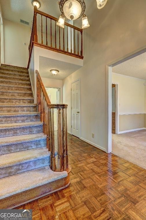 stairs featuring visible vents, a towering ceiling, baseboards, and a textured ceiling