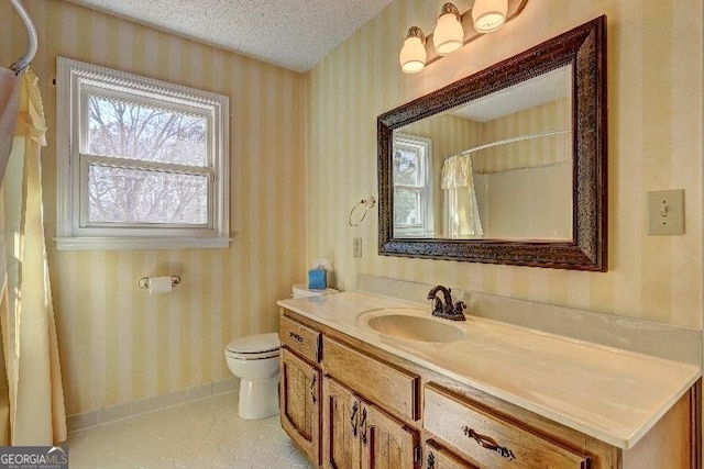 full bath with a textured ceiling, toilet, vanity, tile patterned floors, and wallpapered walls