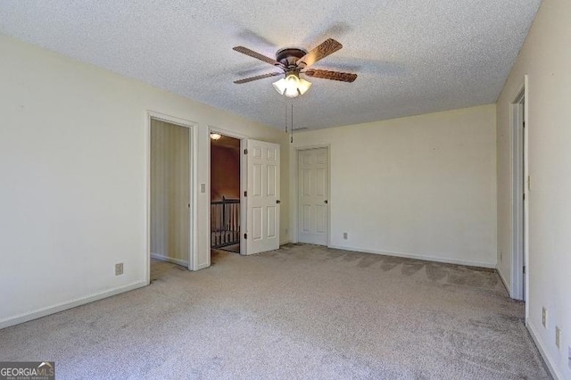 unfurnished bedroom with a ceiling fan, baseboards, a textured ceiling, and light colored carpet