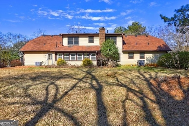 back of house featuring a yard, a chimney, and central air condition unit