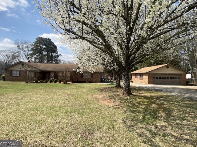 ranch-style home with an outbuilding, a garage, brick siding, and a front lawn