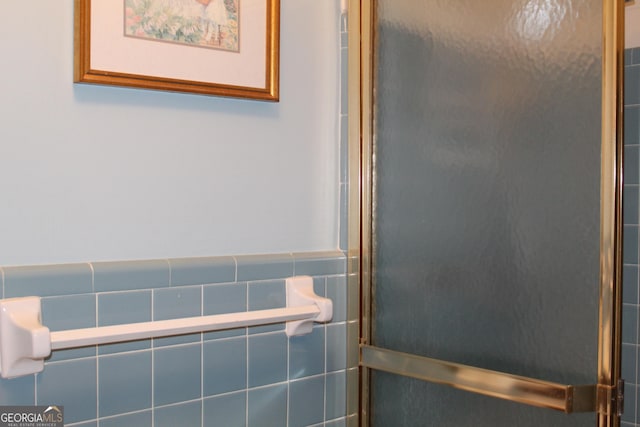 full bath with a wainscoted wall, walk in shower, and tile walls