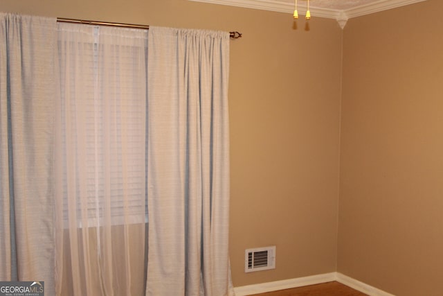 interior space with visible vents, crown molding, baseboards, and wood finished floors