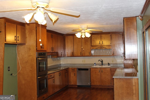 kitchen with stainless steel appliances, dark wood-type flooring, a sink, a ceiling fan, and brown cabinets