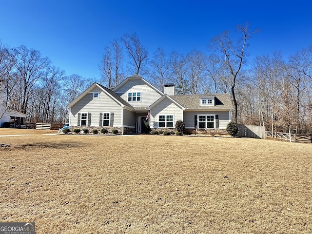 back of house with stone siding, a yard, a chimney, and fence