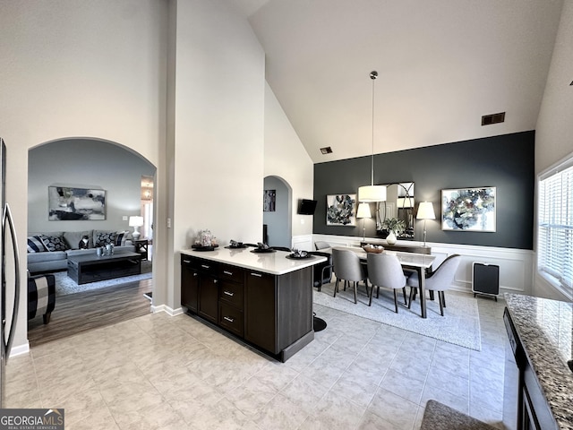 kitchen with pendant lighting, arched walkways, open floor plan, and visible vents