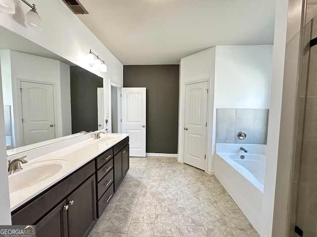 full bathroom featuring visible vents, a sink, a garden tub, and double vanity