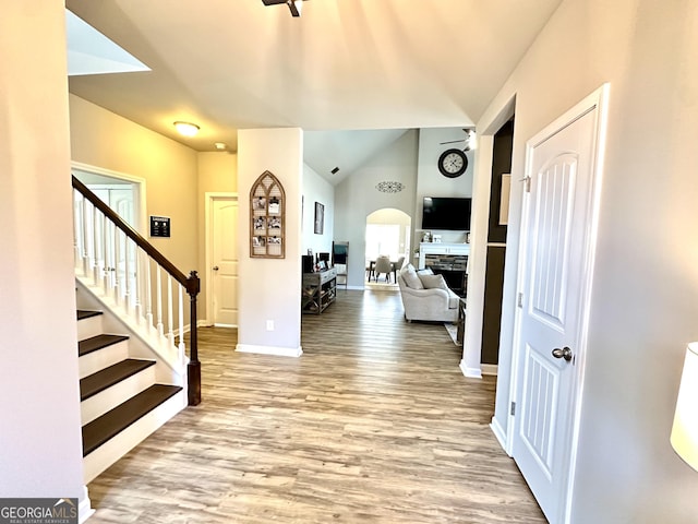 entrance foyer featuring baseboards, a ceiling fan, stairs, vaulted ceiling, and light wood-type flooring