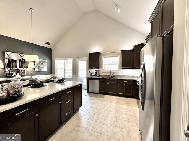 kitchen featuring stainless steel appliances, hanging light fixtures, light countertops, and dark brown cabinetry