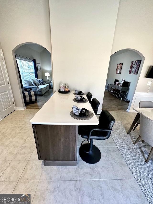 kitchen with a high ceiling, arched walkways, light countertops, and a breakfast bar area