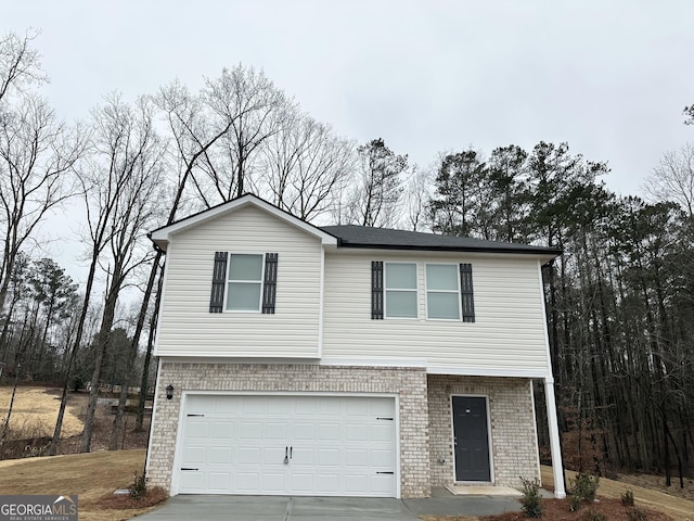 view of front of home with concrete driveway, brick siding, and an attached garage