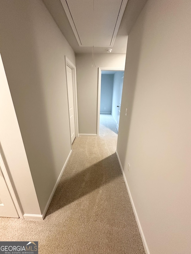 hall with carpet floors, attic access, and baseboards