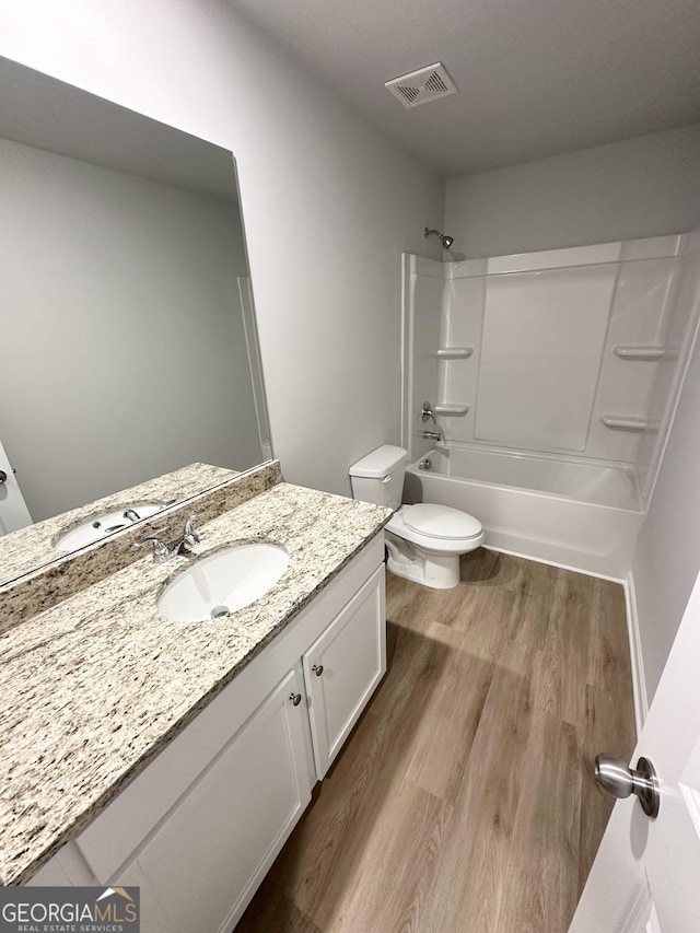 full bathroom featuring visible vents, toilet, vanity, wood finished floors, and  shower combination