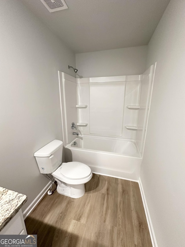 bathroom featuring shower / tub combination, toilet, wood finished floors, vanity, and visible vents