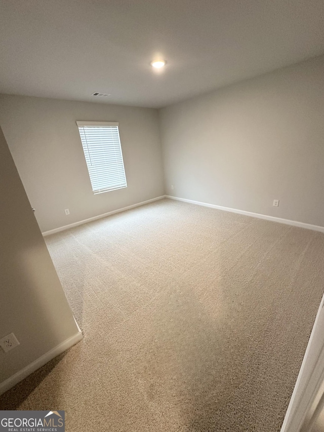 empty room with carpet floors, visible vents, and baseboards