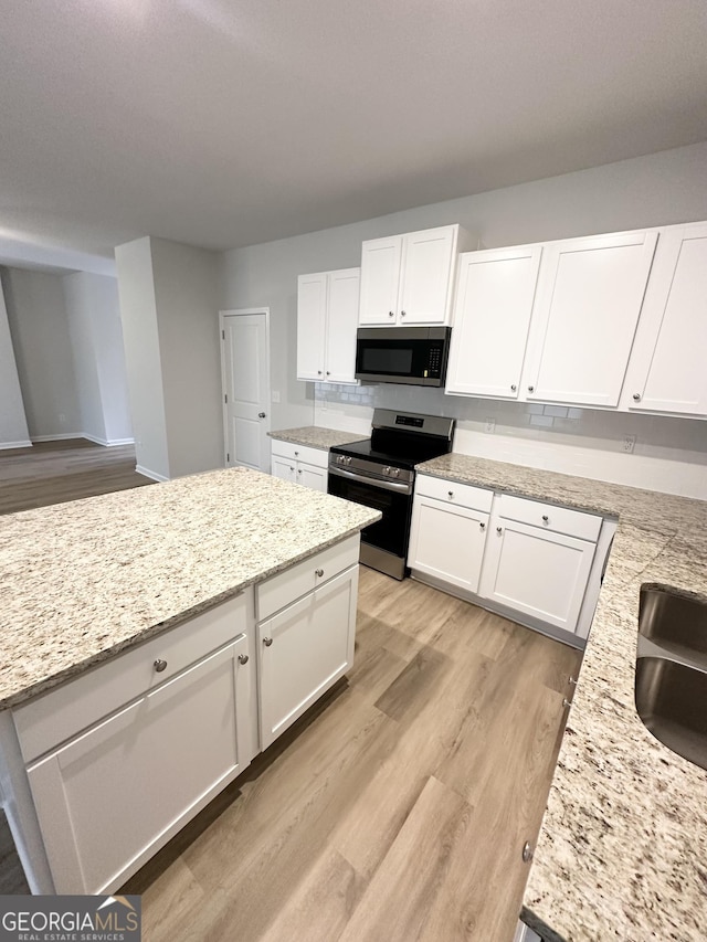 kitchen featuring light wood-type flooring, appliances with stainless steel finishes, white cabinets, and a sink