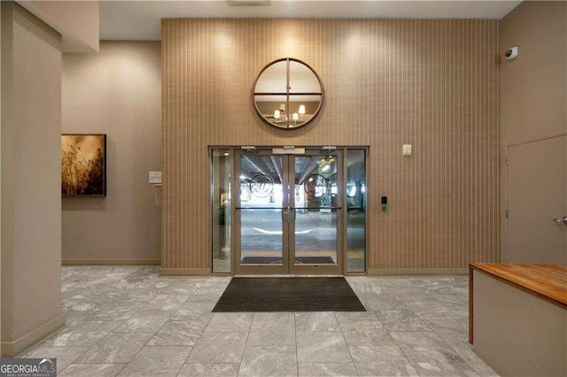 foyer entrance with a chandelier, french doors, and baseboards