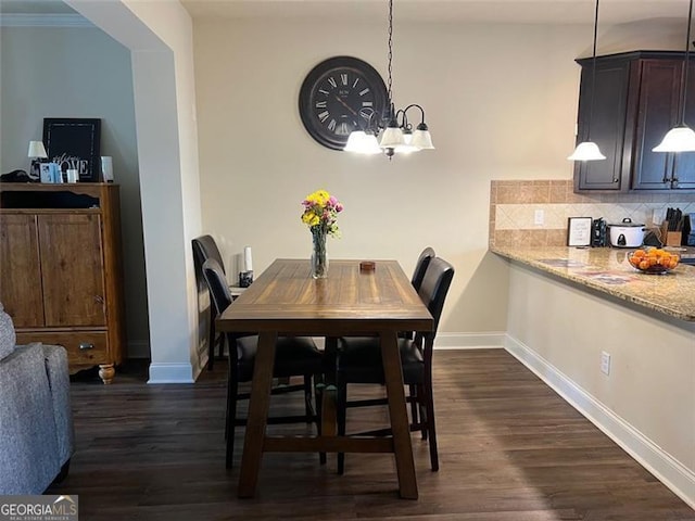 dining area with dark wood-style flooring, a notable chandelier, and baseboards