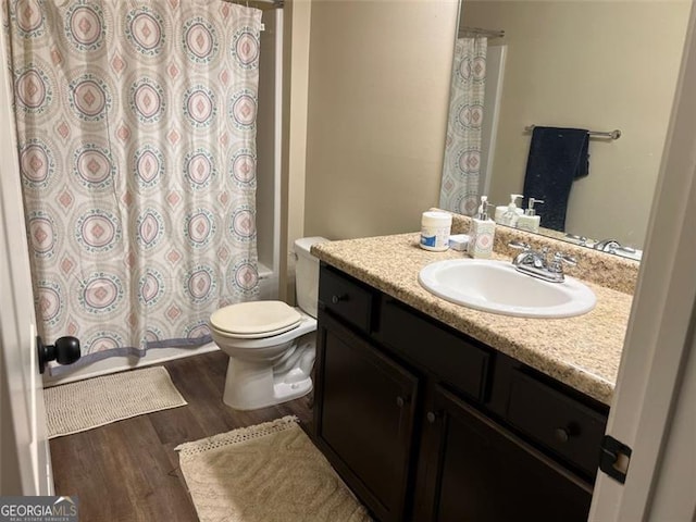 bathroom featuring shower / bathtub combination with curtain, vanity, toilet, and wood finished floors