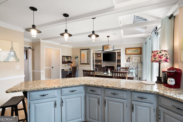 kitchen featuring light stone counters, pendant lighting, a breakfast bar area, open floor plan, and a peninsula