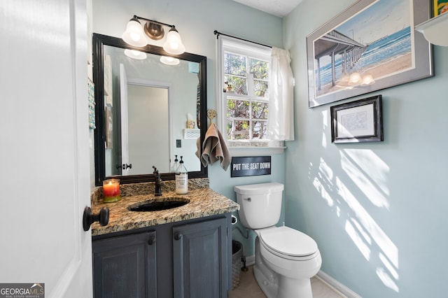 bathroom with toilet, baseboards, and vanity